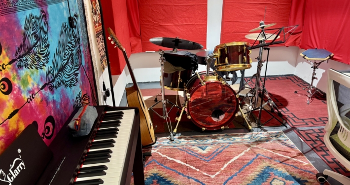 Music studio with a drum, a piano and a desk